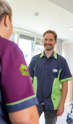 Twee Verzorgende IG collega's kijken elkaar vrolijk aan.